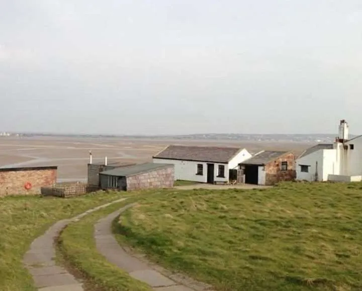 Concrete path leading to the white cottages on Hilbre, with the Dee Estuary at low tide beyond