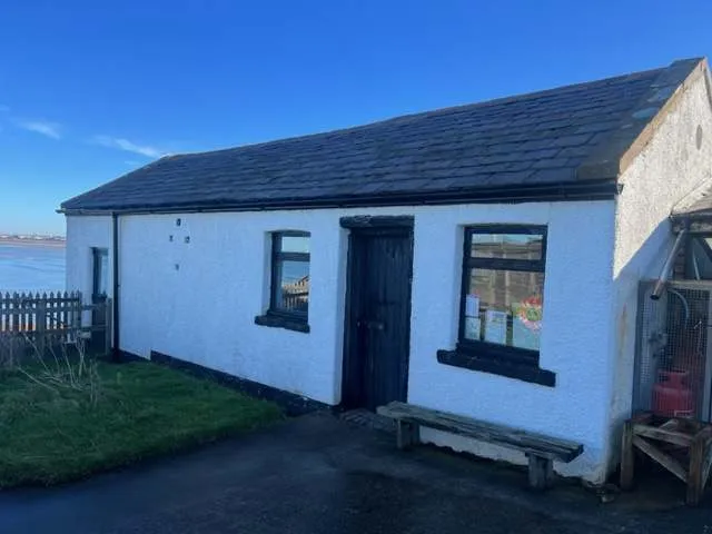White-painted cottage on Hilbre under a clear blue sky